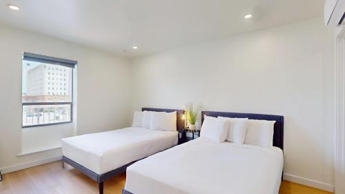 two beds in a white room with a window at Ocean's Edge Luxury Rentals in Ocean City