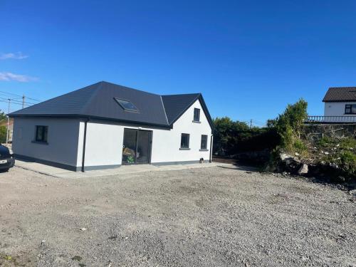 a small white house with a black roof at Blue house, Carraroe in Carraroe