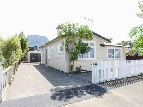 a white house with a white fence next to it at The Cozy Cottage in Napier