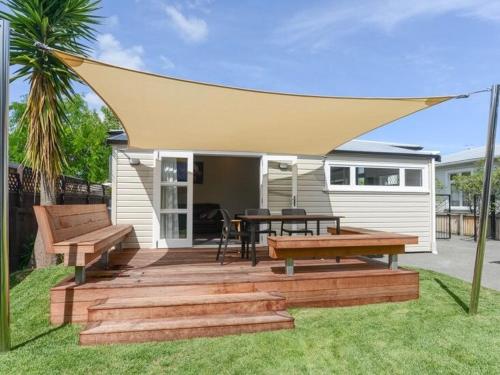 a patio with benches and a table and a tent at The Cozy Cottage in Napier