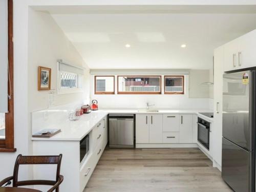 a kitchen with white cabinets and a chair in it at The Cozy Cottage in Napier