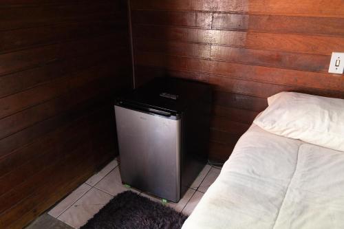 a room with a small refrigerator next to a bed at Cabana do Arqueiro in Campos do Jordão