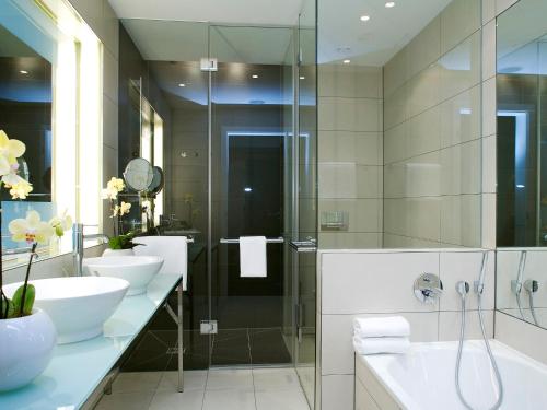 a bathroom with two sinks and a glass shower at Vienna House by Wyndham Andel's Berlin in Berlin