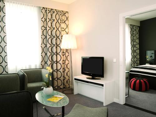a hotel room with a television and a living room at Vienna House by Wyndham Andel's Berlin in Berlin