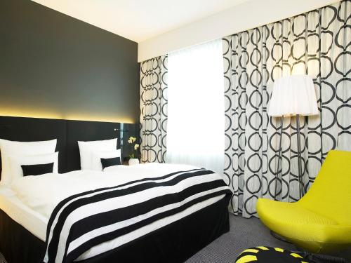a bedroom with a bed and a yellow chair at Vienna House by Wyndham Andel's Berlin in Berlin