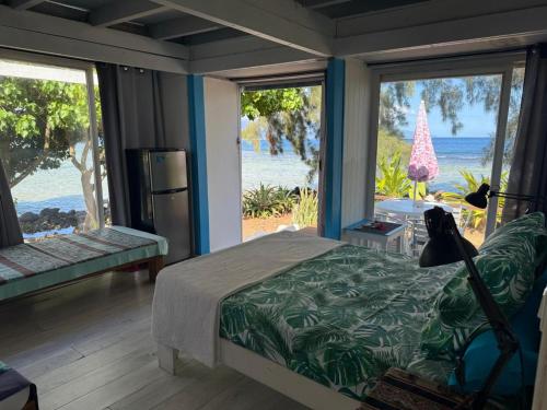 a bedroom with a bed with a view of the ocean at Bungalow les pieds ds l eau, La Maison Bleue in Moorea