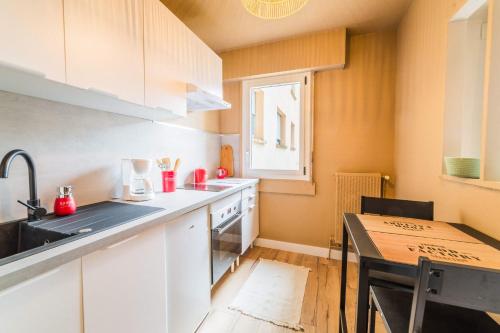 a kitchen with white cabinets and a table and a window at L'Icône de la Guierle - 1 Chambre in Brive-la-Gaillarde