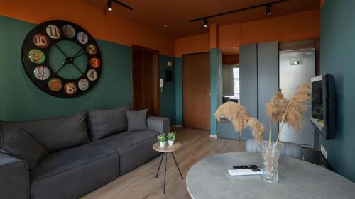 a living room with a couch and a clock on the wall at Cozy apartment in Polisi i Vogël