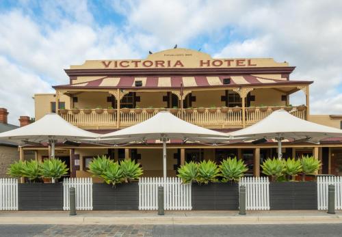 a hotel with white umbrellas in front of it at Victoria Hotel Strathalbyn in Strathalbyn