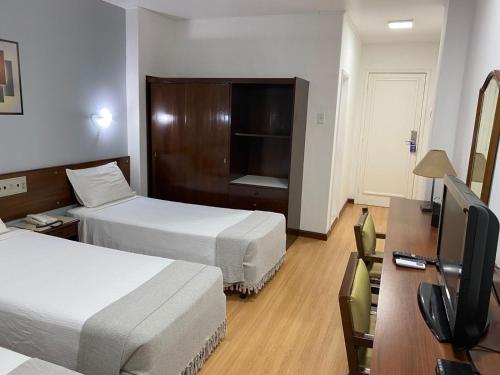 a hotel room with two beds and a flat screen tv at City Hotel- Mercado Publico, Prefeitura Municipal in Porto Alegre