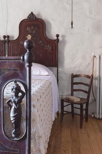 a bedroom with a bed with a statue next to a chair at WUNDERGARTEN Dimora dei Frati in Gratteri