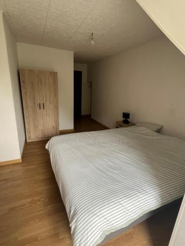 une chambre avec un lit blanc et un parquet dans l'établissement Appartement Mauriac, à Mauriac