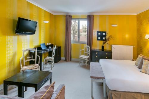 Elle comprend un salon avec des murs jaunes, un lit et un bureau. dans l'établissement Best Western Hotel Le Guilhem, à Montpellier