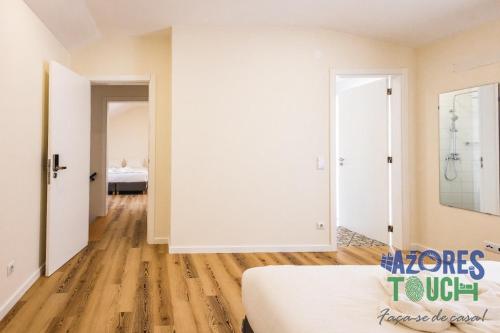 a bedroom with white walls and wooden floors and a bed at Hostel Casa São Pedro - Suíte 1 in Angra do Heroísmo