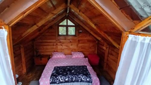 a bedroom in a log cabin with a bed in it at Cabaña en el Campo in La Vega