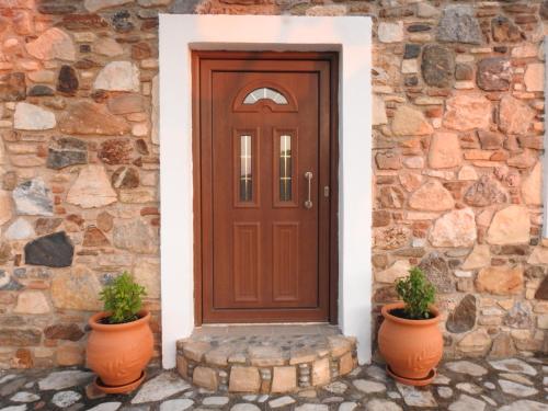 eine Holztür auf einer Steinmauer mit zwei Pflanzen in der Unterkunft The Stone Cottage Kos in Kos-Stadt