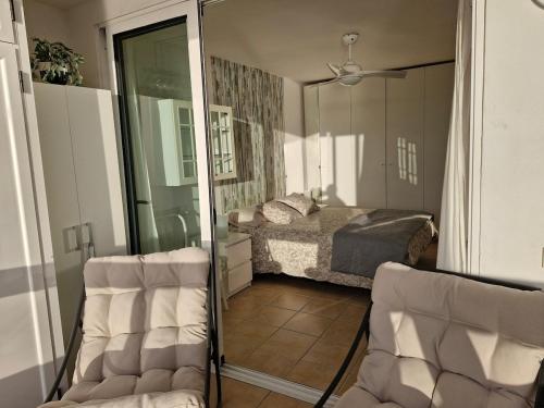 a bedroom with a bed and a glass door with two chairs at Patalavaca beach apartment with stunning ocean view in Patalavaca