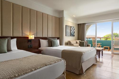 a hotel room with two beds and a balcony at Grand Palladium Imbassaí Resort & Spa - All Inclusive in Imbassai