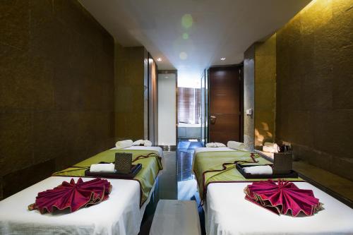 a room with three beds with white and red sheets at Novotel Kolkata Hotel and Residences in Kolkata