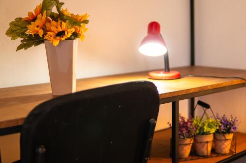 a desk with a vase of flowers and a lamp at Casa Dorada in León