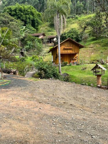 a house on a hill with a dirt road in front at Sítio Som das Águas in Benedito Novo