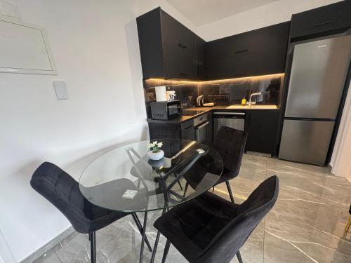 a kitchen with a glass table and black chairs at Limassol Beautiful Apartment II in Limassol