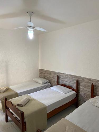 a room with three beds and a ceiling at Pousada nascente do sol in Macaé