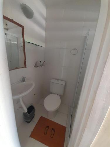 a bathroom with a toilet and a sink and a mirror at Pousada nascente do sol in Macaé