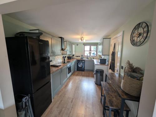 a kitchen with a black refrigerator and a table at Purdie Close Holiday Let in Cheddar