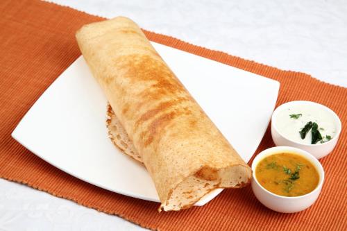 a white plate with a sandwich and a dipping sauce at Hotel O Black Pearl Residency in Pīlamedu