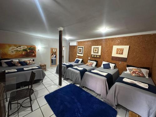 a room with four beds and chairs in it at Pousada Pesque Pague Jango in Cuiabá