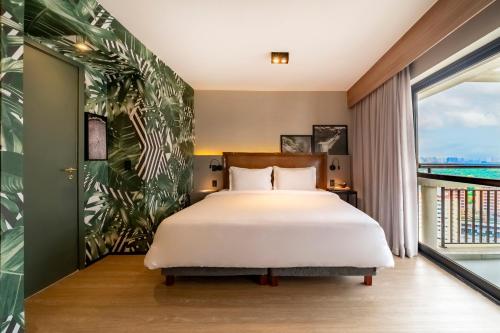 a bedroom with a bed and a large window at Grand Mercure SP Itaim Bibi in São Paulo
