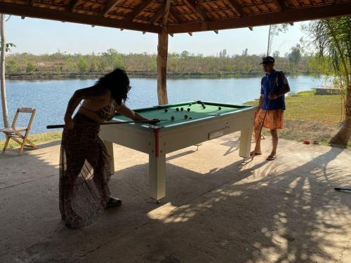 a woman playing a game of billiards on a pool table at Pousada Pesque Pague Jango in Cuiabá