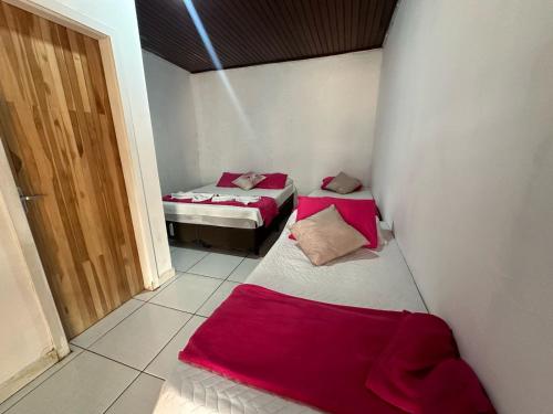 two beds in a small room with red sheets at Pousada Pesque Pague Jango in Cuiabá