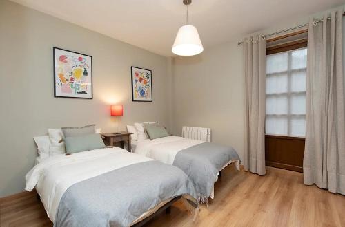 a bedroom with two beds and a window at El Bosque del Sapo in El Pueyo de Jaca