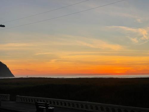 a sunset over the ocean with a bench in the foreground at Seaside Beach Front House on the Promenade in Seaside