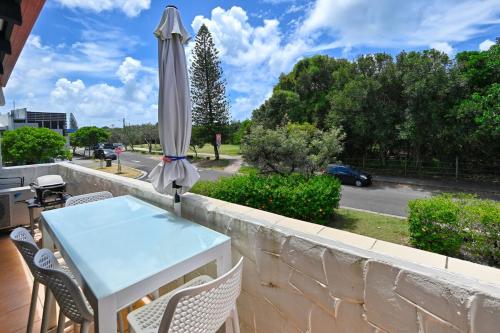 a table and an umbrella on a balcony at Beachfront 1BR and Loft Bliss Surf Cafe Escape in Marcoola