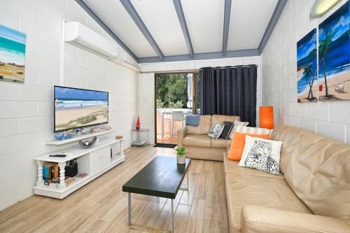 a living room with a couch and a tv at Beachfront 1BR and Loft Bliss Surf Cafe Escape in Marcoola