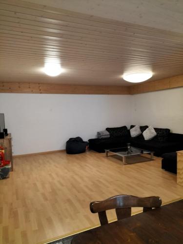 a living room with a black couch and a wooden floor at Grosszügige, charmante Wohnung in den Bergen in Breiten