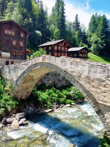 a stone bridge over a river in front of houses at Grosszügige, charmante Wohnung in den Bergen in Breiten
