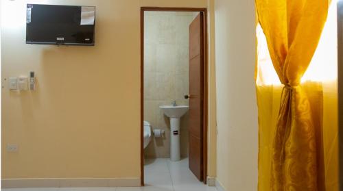 a bathroom with a toilet and a television on the wall at hotel casa martin in Gaira