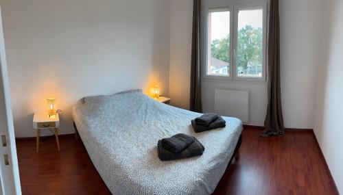 - une chambre avec un lit et 2 serviettes noires dans l'établissement Maison proche plage avec jacuzzi, à Ondres