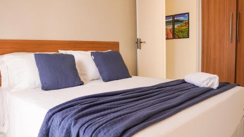 a bedroom with a large bed with blue and white sheets at Apartamento Frente Mar in Arraial do Cabo