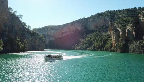a boat traveling down a river in a canyon at Ignis Rural Apartment - Casillas Valle de Ayora in Jalance