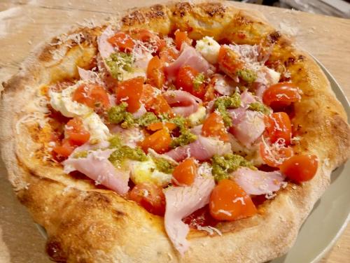 a pizza with ham and vegetables on a plate at Ignis Rural Apartment - Casillas Valle de Ayora in Jalance
