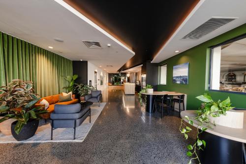 a living room with green walls and furniture and plants at Sage Hotel James Street in Brisbane
