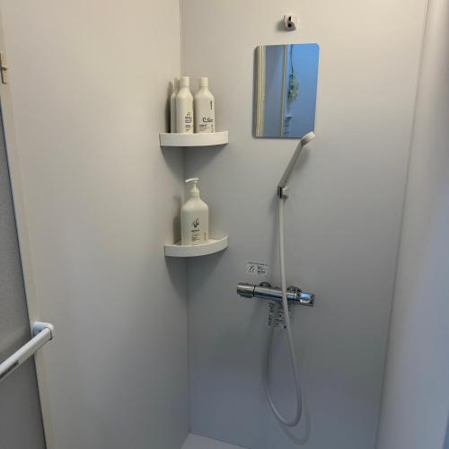 a bathroom with a shower with a mirror and shelves at Stay&Work HIRAJO in Yokote