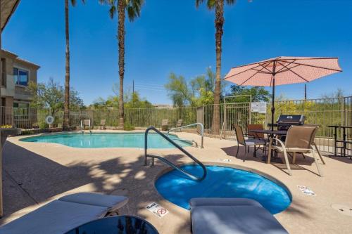 a swimming pool with a table and an umbrella at Panorama View - Mountain Views - Community Pool in Fountain Hills