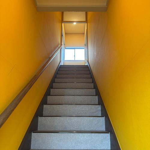 a flight of stairs in a building with yellow walls at Stay&Work HIRAJO in Yokote