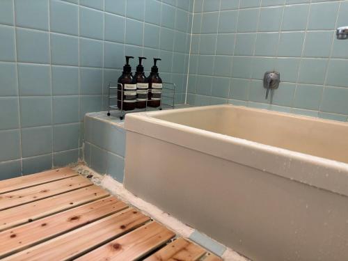 a bathroom with a tub and three bottles of alcohol at A cozy home between Osaka and Kyoto -UNiCO- in Takatuki